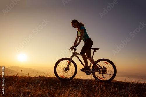 Biker-girl at the sunset on mountains