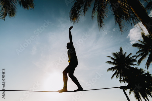 teenage girl  balancing on slackline with sky view photo