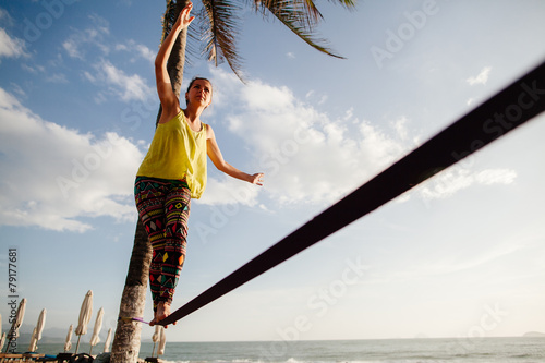 teenage girl  balancing on slackline with sky view photo