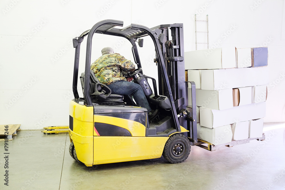 Forklift truck in warehouse or storage loading cardboard boxes