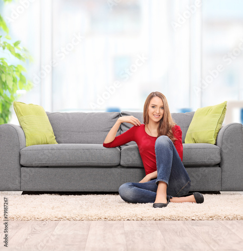 Relaxed young woman sitting by a sofa
