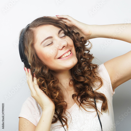 Young curly woman with headphones listening music.