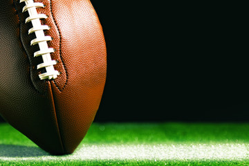 American football on green grass, on black background