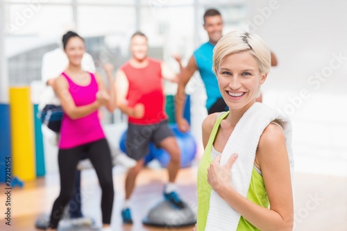 Portrait of happy woman holding towel at gym
