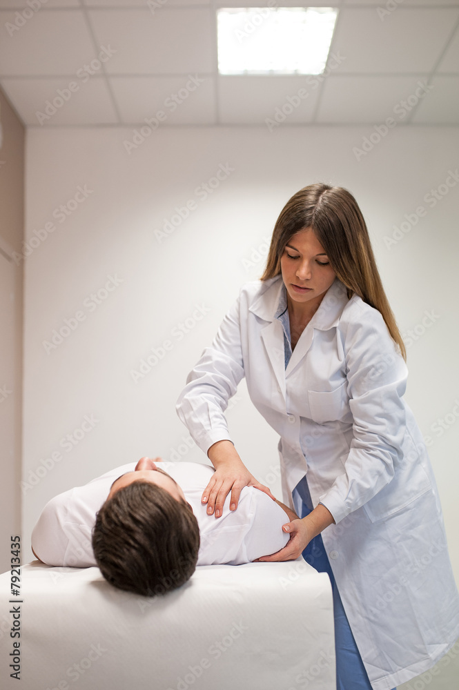 Female doctor physiotherapist practicing massage to her male pat Female doctor physiotherapist practicing massage to her male pat
