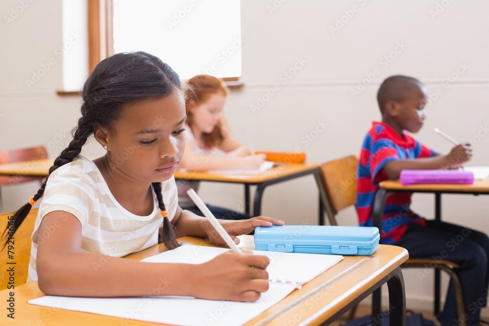 Cute pupils writing at desk in classroom Cute pupils writing at desk in classroom