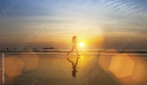 Young girl silhouette Jogging on sea beach .