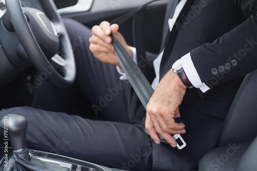 Businessman putting on his seat belt