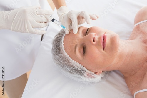 Woman receiving cosmetic injection in her forehead