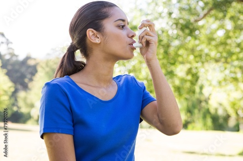 Pretty woman using her inhaler