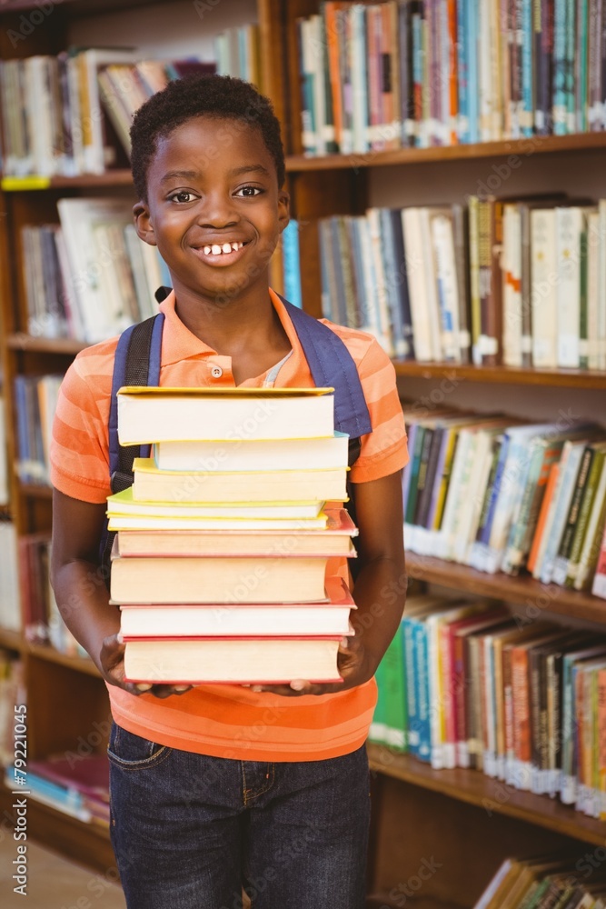 Cute little boy carrying books in library Cute little boy carrying books in library