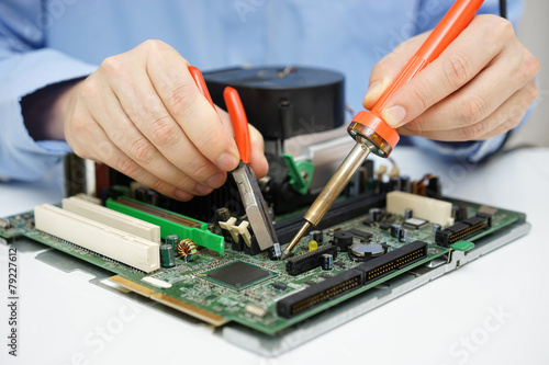 Computer technician is changing capacitor on faulty motherboard