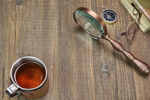 Compass, Magnifying Glass, Tea Mug, Two Notebooks on Wood Table photo