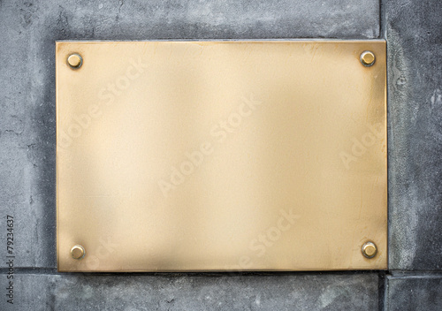 blank gold or brass metal sign or nameboard on concrete wall