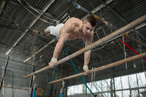 Athlete topless doing exercises on the uneven bars © Andriy Bezuglov