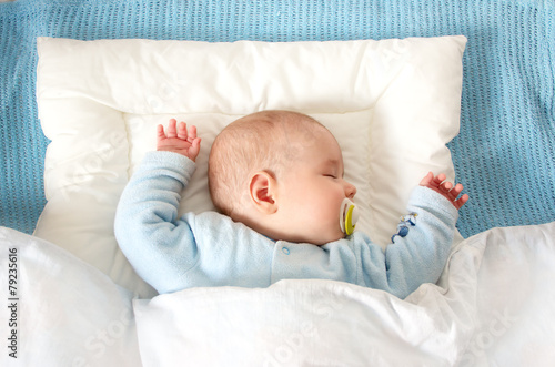 Four month old baby sleeping on blue blanket