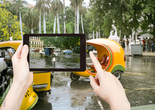 Photography tourist taking photo of Havana street in rain