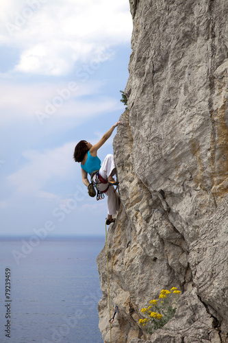 Female climber climbs wall in over the sea
