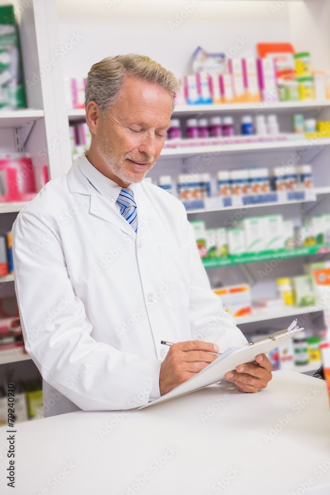 Senior pharmacist writing a prescription on clipboard