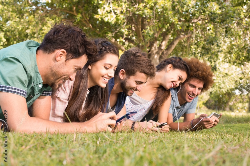 Happy friends in the park using their phones Happy friends in the park using their phones