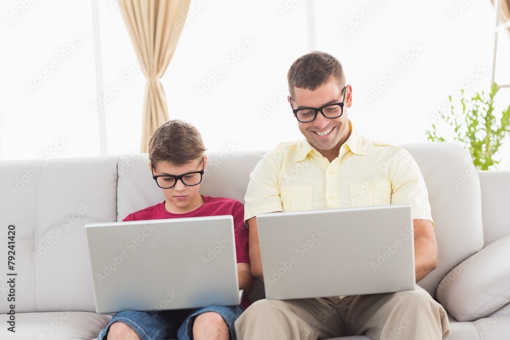 Father and son wearing novelty glasses while using laptop Father and son wearing novelty glasses while using laptop