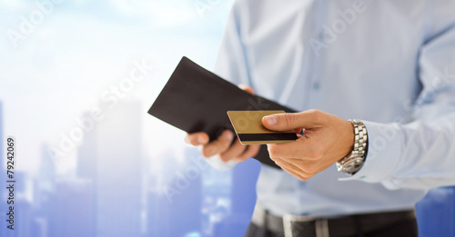 close up of man holding wallet and credit card