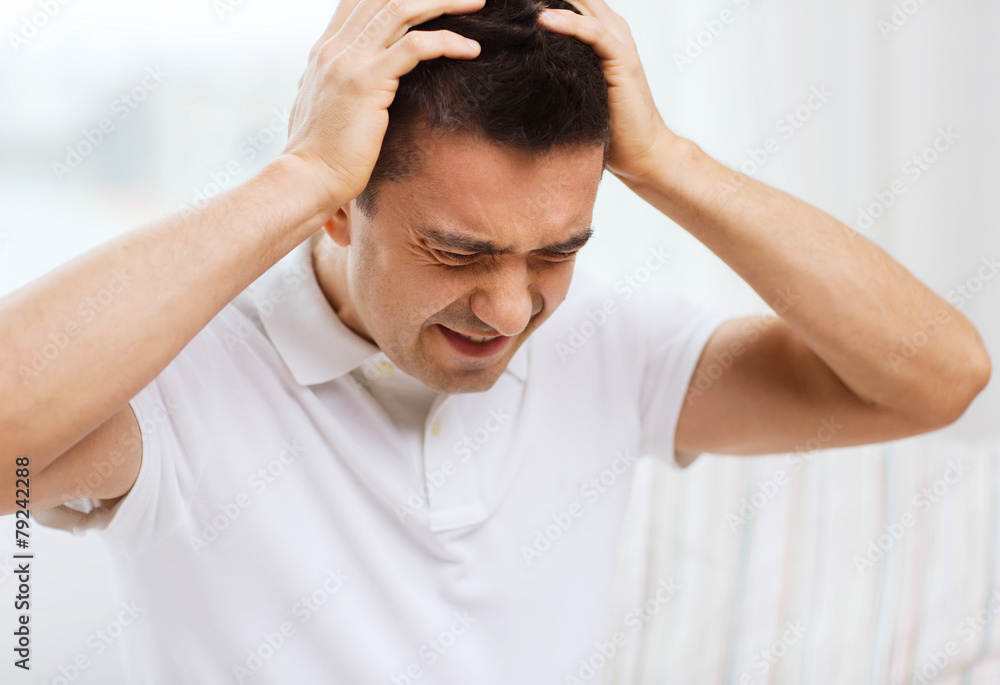 unhappy man suffering from head ache at home unhappy man suffering from head ache at home