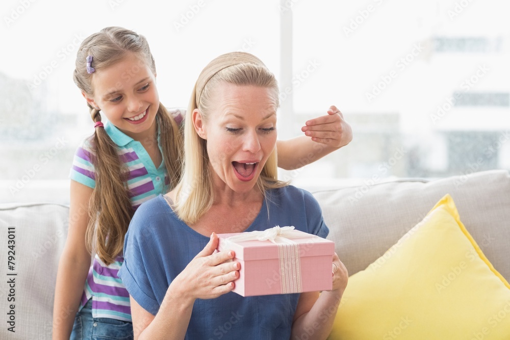 Happy girl surprising her mother with gift at home Happy girl surprising her mother with gift at home