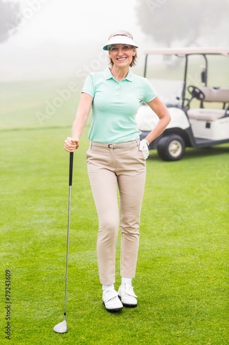 Happy golfer with golf buggy behind © WavebreakmediaMicro