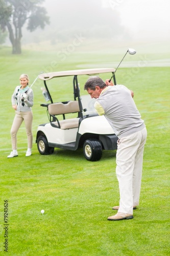 Golfer about to tee off with partner behind him