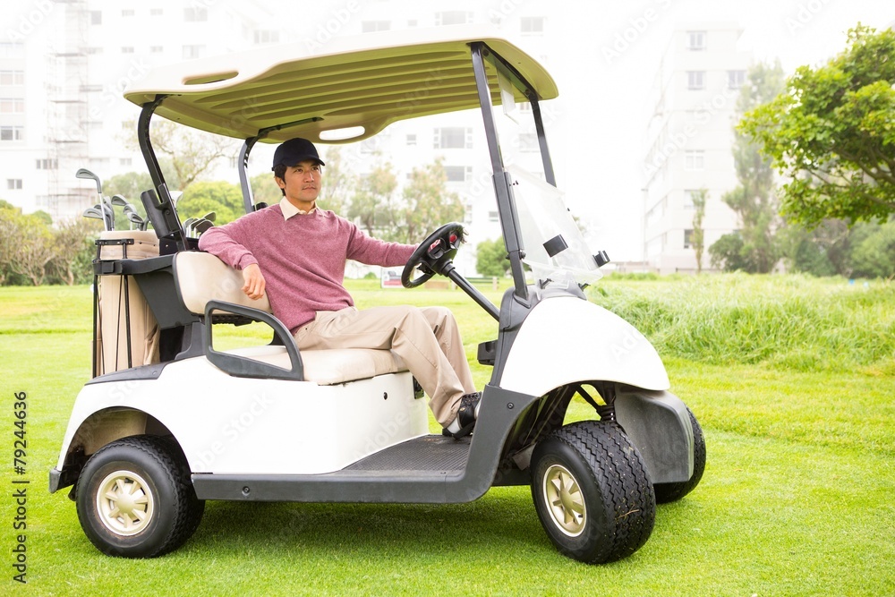 Golfer driving his golf buggy looking at camera Golfer driving his golf buggy looking at camera