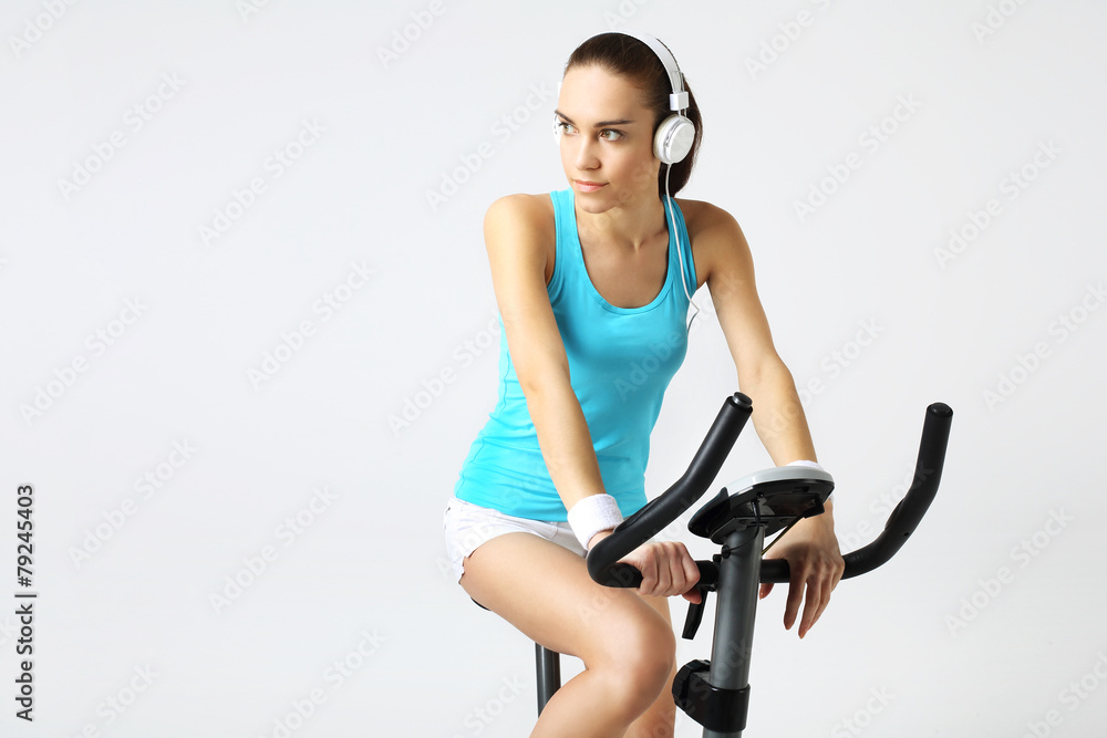 Naklejka premium Ćwiczenia na rowerze stacjonarnym, kobieta w fitness klubie