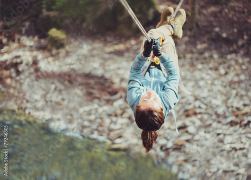 Woman crossing a river with tyrolean traverse