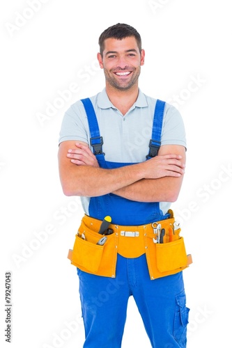 Repairman in overalls wearing tool belt standing arms crossed