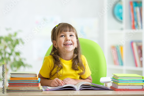 smiling child girl reading book at home