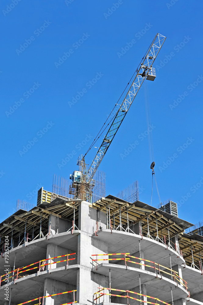 Crane and building construction site against blue sky Crane and building construction site against blue sky