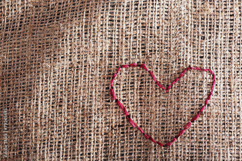 Linen canvas with red heart embroidered on it, close-up