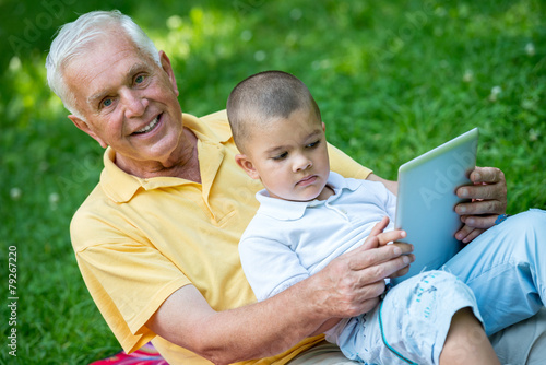 grandfather and child in park using tablet