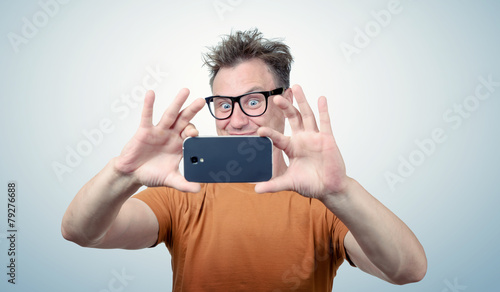 Happy man in glasses photographed by smartphone