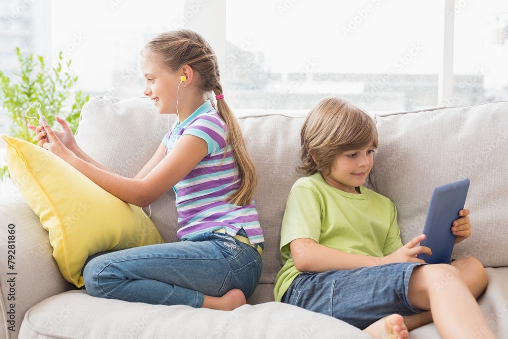 Siblings using technologies on sofa Siblings using technologies on sofa