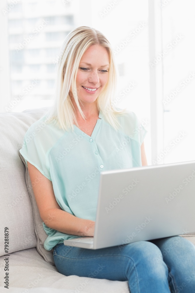 Young woman using laptop while sitting on sofa Young woman using laptop while sitting on sofa