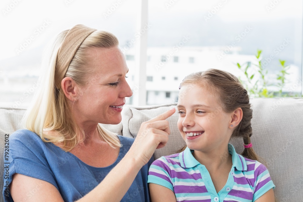 Mother touching daughter in living room Mother touching daughter in living room