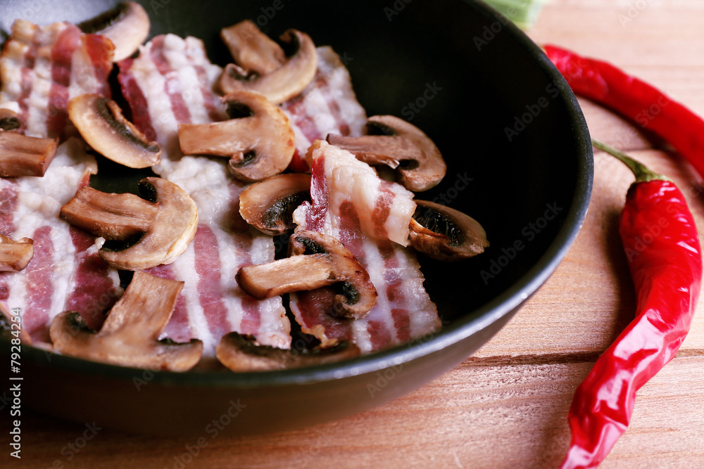 Strips of bacon in pan with mushrooms, shallot and chili pepper