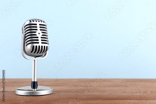 Retro microphone on wooden table on light background