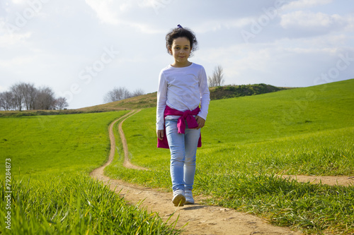 Niña corriendo y caminando feliz por el camino en el campo