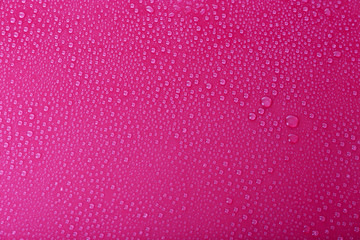 Water drops on glass on pink background