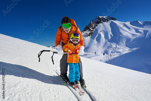 Father give mountain ski lesson to little boy