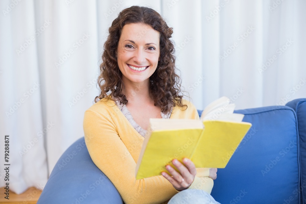 Pretty brunette relaxing on the couch and reading book Pretty brunette relaxing on the couch and reading book