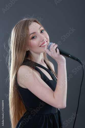 Portrait of a beautiful blonde young woman singing into micropho photo