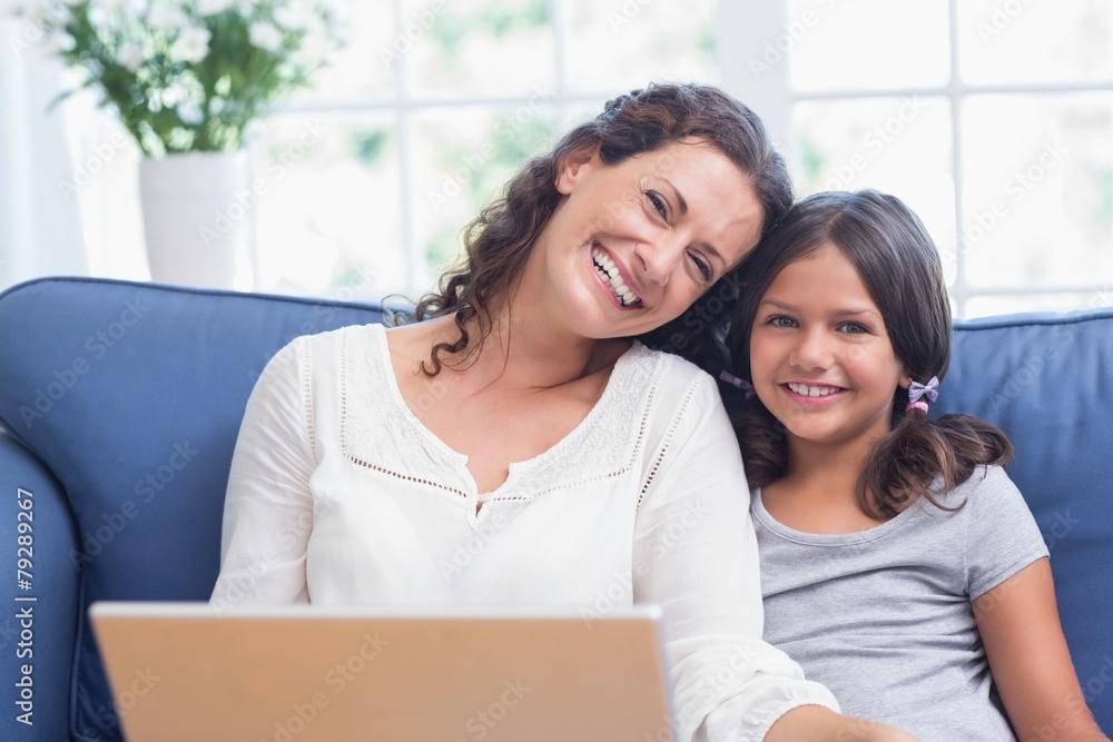 Happy mother and daughter sitting on the couch and using laptop Happy mother and daughter sitting on the couch and using laptop
